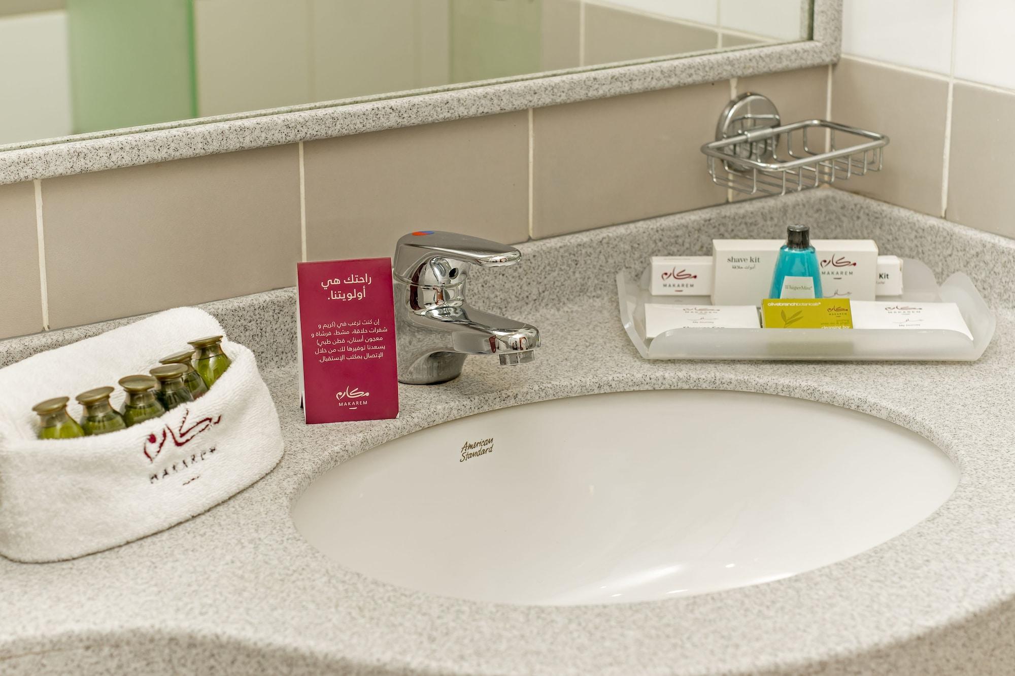 Makarem Umm Al Qura Hotel Mecca Exterior foto The photo shows a bathroom sink area with a modern faucet and a circular sink. Surrounding the sink is a light-colored countertop. 

To the left, there is a white towel with a logo. Nearby, there are several small bottles and containers of toiletries