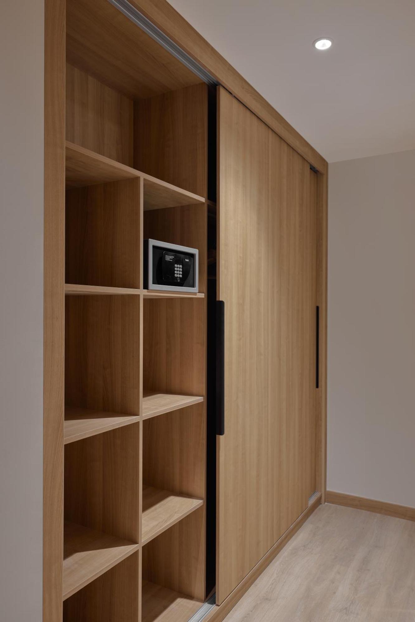 Makarem Umm Al Qura Hotel Mecca Exterior foto The photo shows a wooden wall feature with a series of open shelves on one side and a sliding door on the other. The shelves are empty except for a small electronic safe or lockbox positioned in the middle section. The wooden finish gives it a warm, 