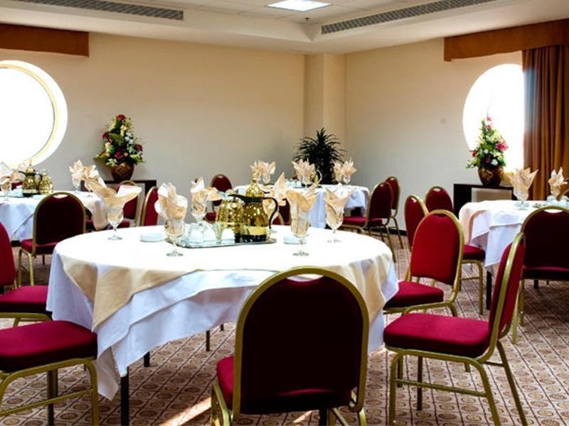 Makarem Umm Al Qura Hotel Mecca Exterior foto The photo features a well-decorated dining or event room. It has several round tables covered with white tablecloths, each set with decorative napkins. The chairs around the tables are upholstered in red. There are also floral arrangements in vases p
