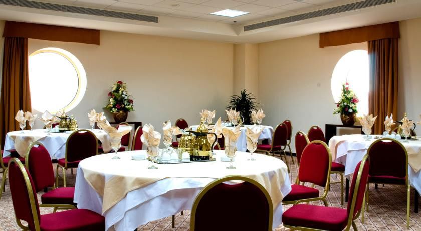 Makarem Umm Al Qura Hotel Mecca Exterior foto The photo depicts a dining or event space set up for a gathering. It features several round tables covered with white tablecloths. Each table is adorned with elegant decorations, including folded napkins and decorative centerpieces. There are gold an