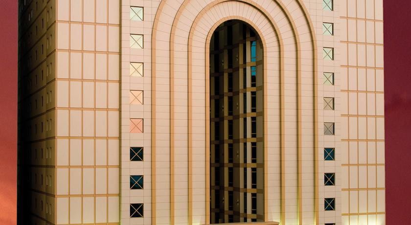 Makarem Umm Al Qura Hotel Mecca Exterior foto The photo shows a section of a building facade featuring a large arch-shaped opening with a frame, surrounded by rectangular patterns. The exterior wall appears to be made of light-colored materials, and there are several geometric shapes, such as sq