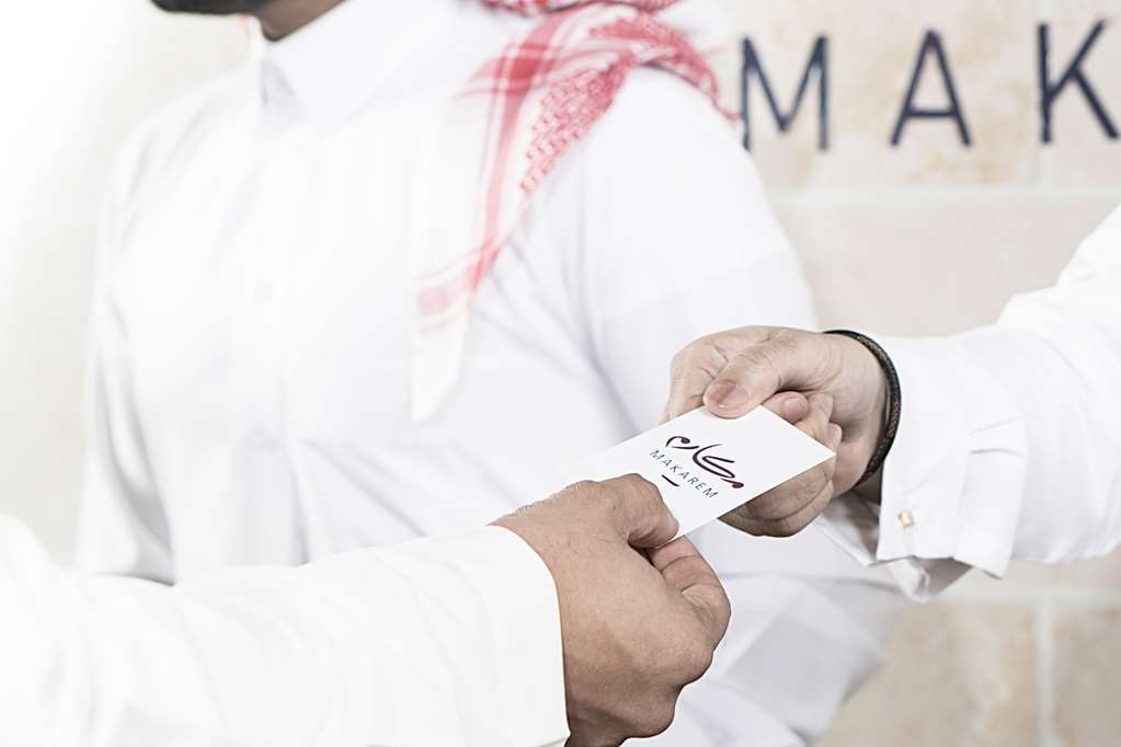Makarem Umm Al Qura Hotel Mecca Facilități foto The photo depicts two individuals engaged in a handover, where one person is passing a business card to another. The person receiving the card appears to be wearing a traditional garment. The background seems to suggest a professional or formal setti