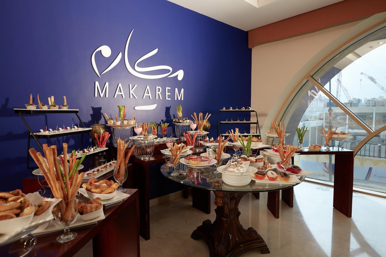 Makarem Umm Al Qura Hotel Mecca Exterior foto The photo depicts a catering setup in a venue named "Makarem." The setup features a variety of dishes displayed on tables. There are multiple plates and decorative elements, including food items such as pastries, desserts, and possibly appetizers. Th