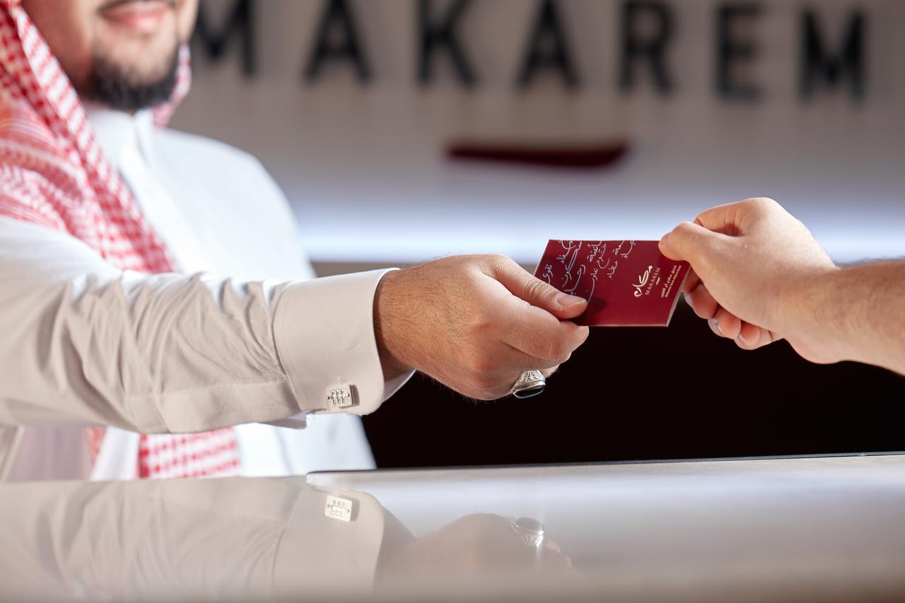 Makarem Umm Al Qura Hotel Mecca Exterior foto The photo shows a hotel reception scene where a man, dressed in traditional attire, is handing over a card to another person. The setting appears to be a hotel lobby, with the name "MAKAREM" visible in the background. The focus is on the interaction 