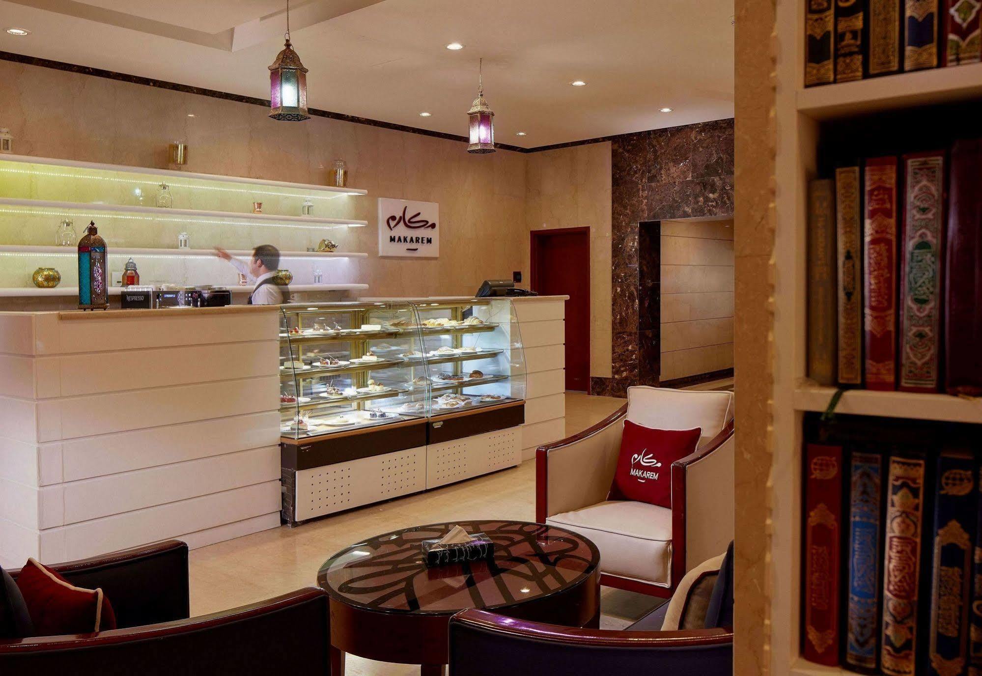 Makarem Umm Al Qura Hotel Mecca Exterior foto The photo shows a stylish interior of a reception area, likely from a boutique hotel or a luxurious establishment. The front desk is modern and well-lit, with a glass display case showcasing various items. There are elegant seating arrangements, incl